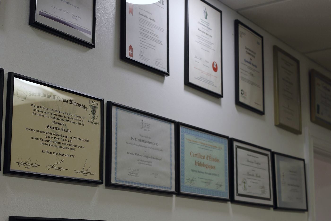 A wall of framed professional certificates and qualifications at PRC Clinic.
