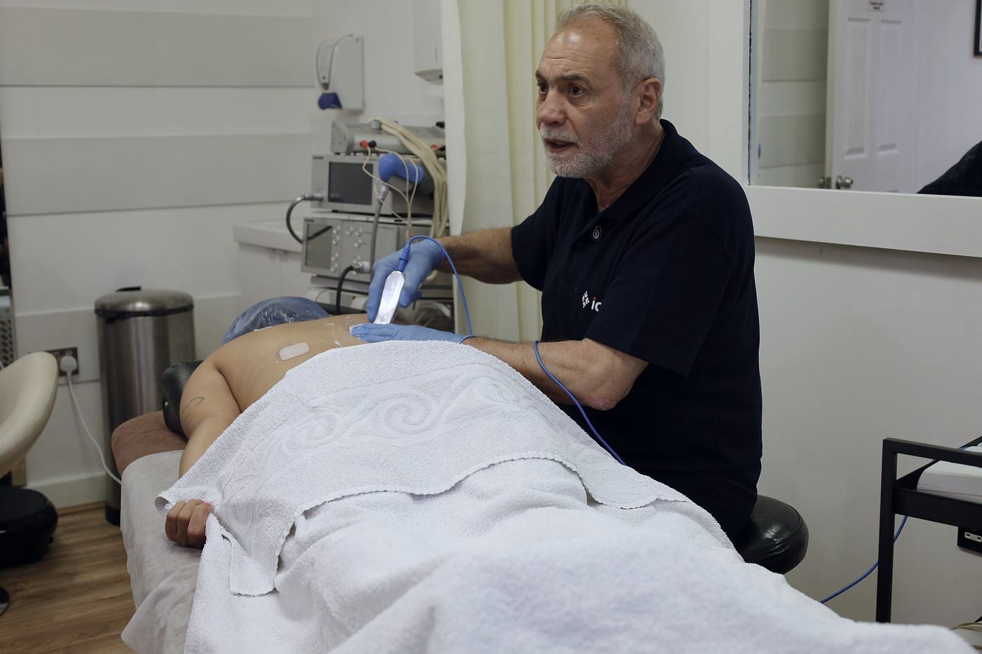 An MSK specialist treating a patient lying on a treatment couch in the PRC Clinic treatment room.